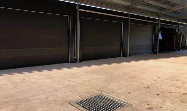 Multiple dark roller doors installed across a large shed