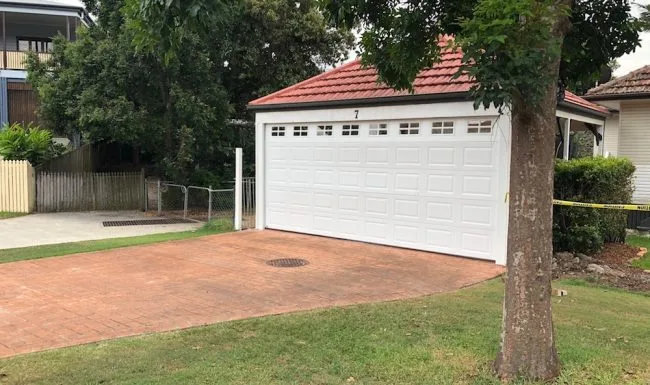 White raised-panel garage door with top windows on a tile-roofed garage